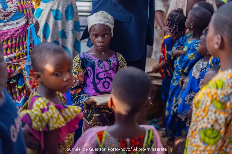 Des enfants rassemblés pour recevoir leurs kits lors de la Journée de Guérison et de Solidarité à Akpro-Missérété ; une fillette tient son cadeau